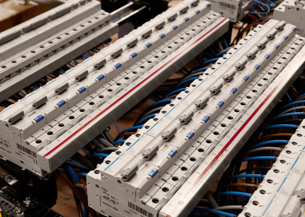 An open electrical distribution panel with multiple circuit breakers, busbars, and labeled wiring connections neatly arranged inside.